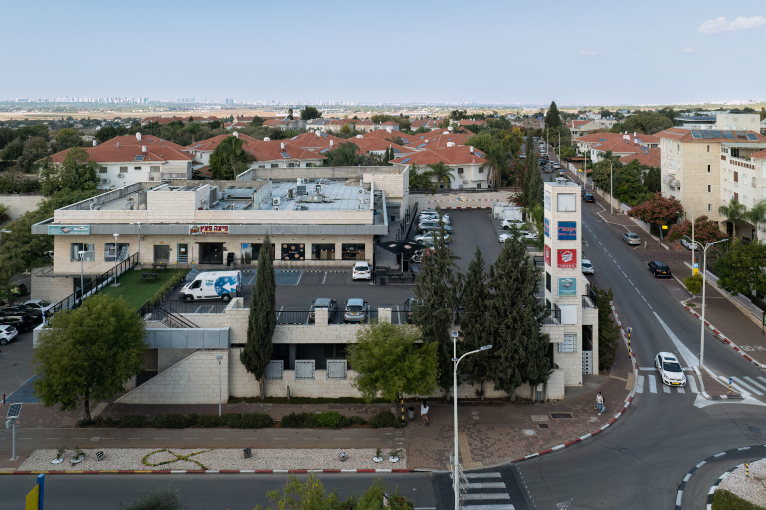 צילום חוץ של מבנה מסחרי, מקומות חנייה, מכוניות, כבישים ובניינים