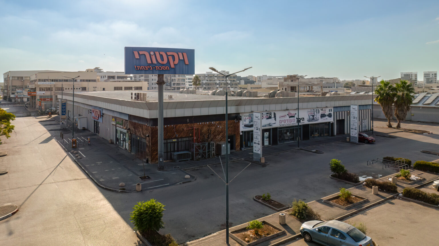 צילום חוץ של מבנה עם השלט ״ויקטורי״, ומקומות חנייה